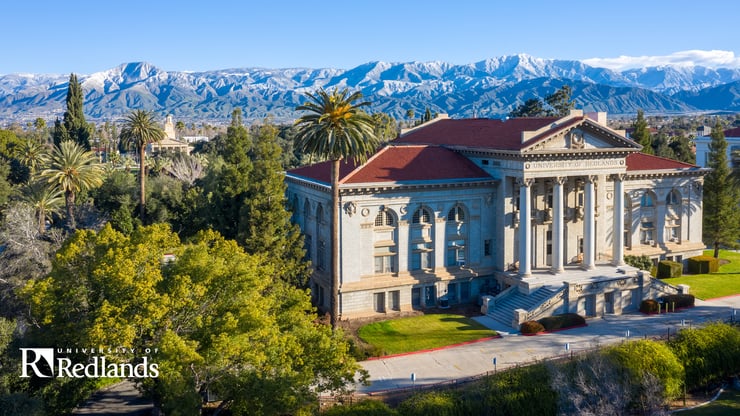 An aerial shot of Redlands University, with the admissions building in the front, and the mountains in the back.